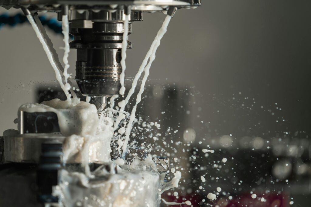 Dynamic close-up of CNC machine with coolant splashing during metalwork operation.