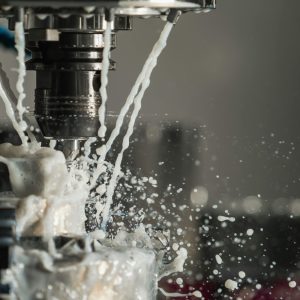 Dynamic close-up of CNC machine with coolant splashing during metalwork operation.